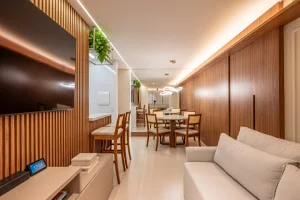 Projeto de sala com painéis amadeirados e mobília em linho off white