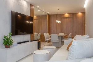 Projeto de sala integrada com cozinha americana, painéis amadeirados e ripado, além de elementos como jardim suspenso e lustre LED.